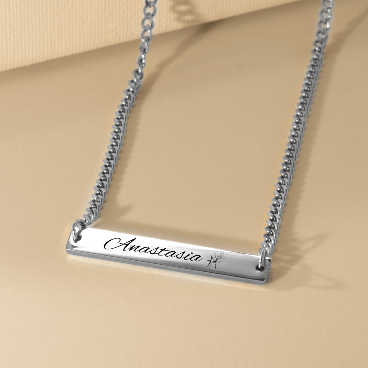 De zilverkleurige cuban link ketting met gegraveerde staaf, liggend van dichtbij