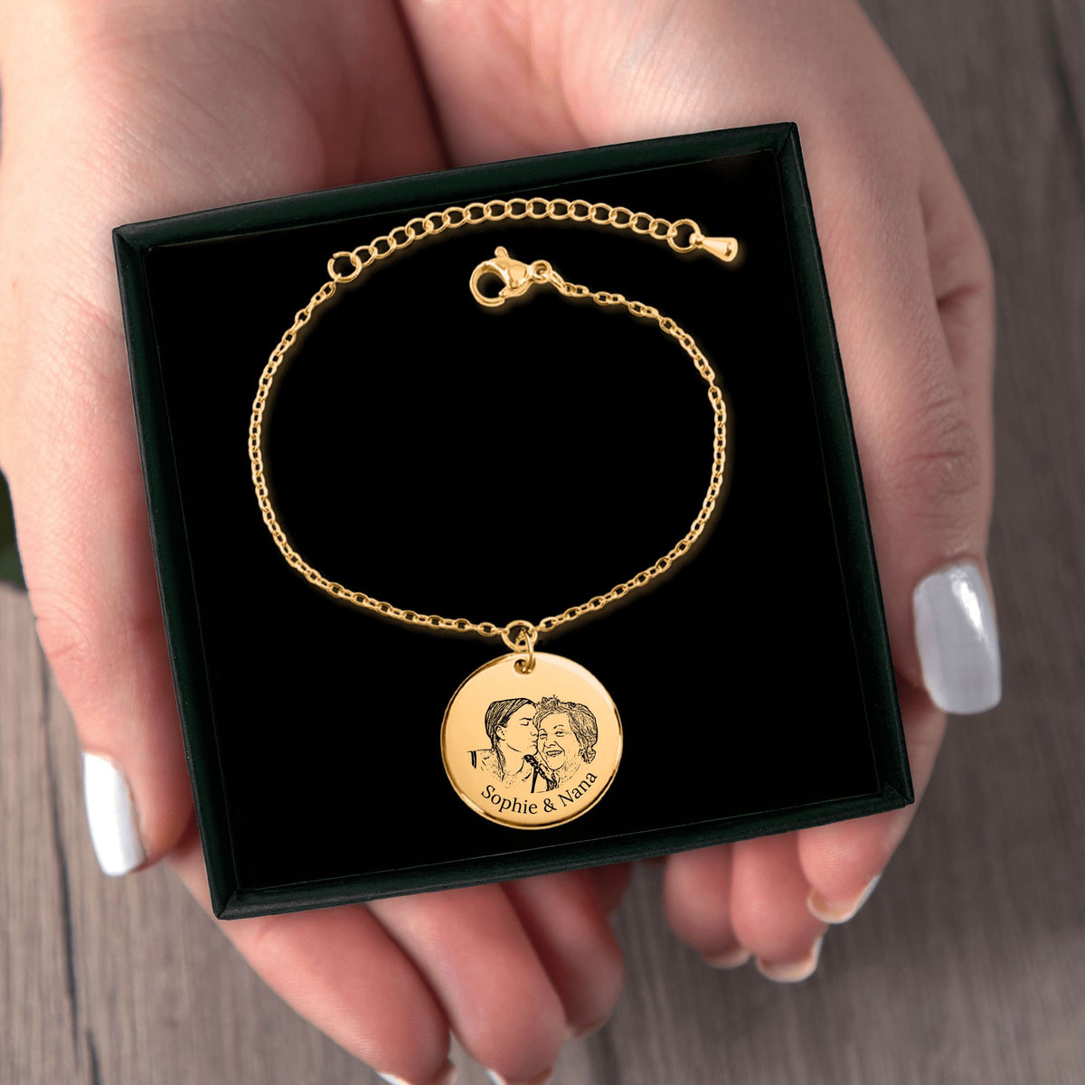 Het geschenkdoosje met de gouden muntarmband, in twee handen