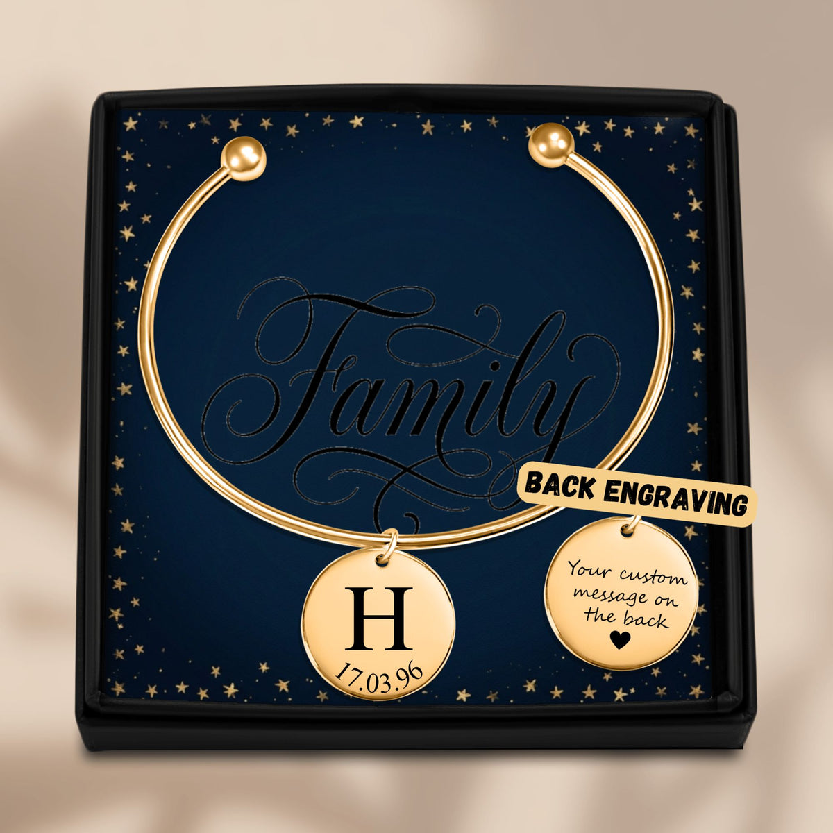 De gouden bangle met gegraveerde hanger in het geschenkdoosje, met de achterkant ernaast