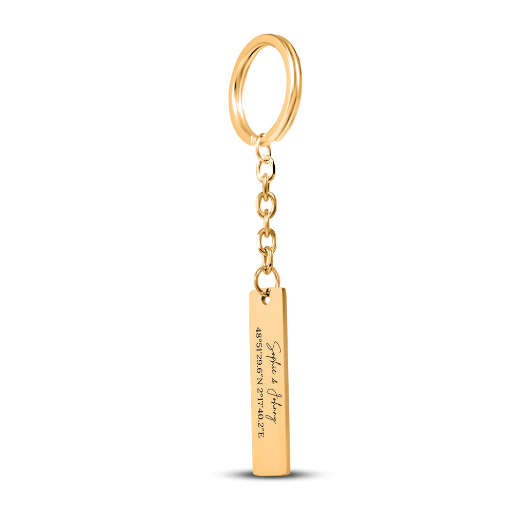 De gouden staafsleutelhanger met ring en ketting, tegen wit