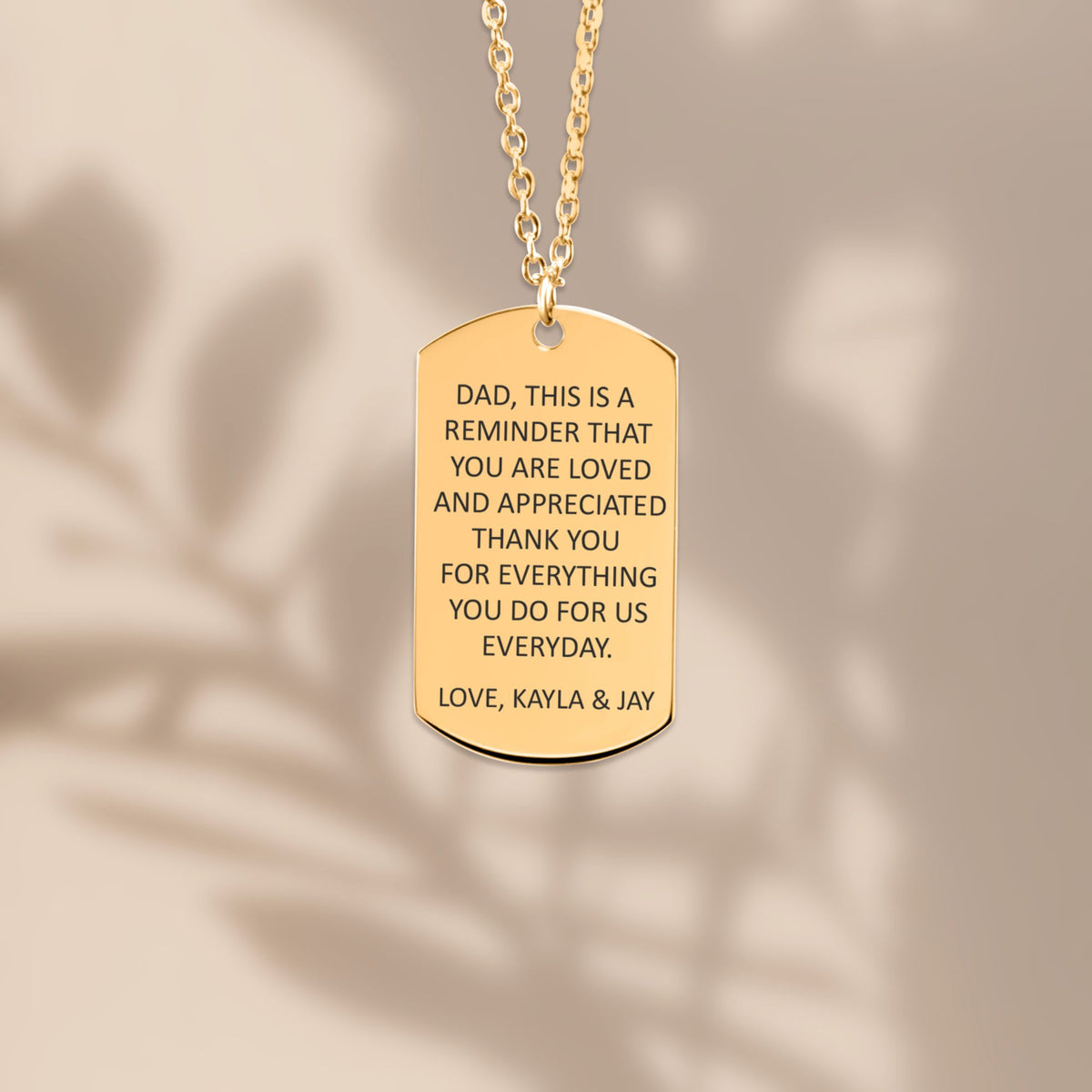 De gouden ketting met gegraveerd plaatje, hangend van dichtbij