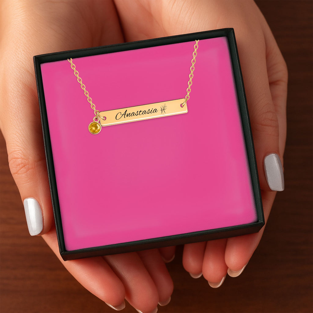 Het geschenkdoosje met de gouden horizontale staafketting met geboortesteen, in twee handen