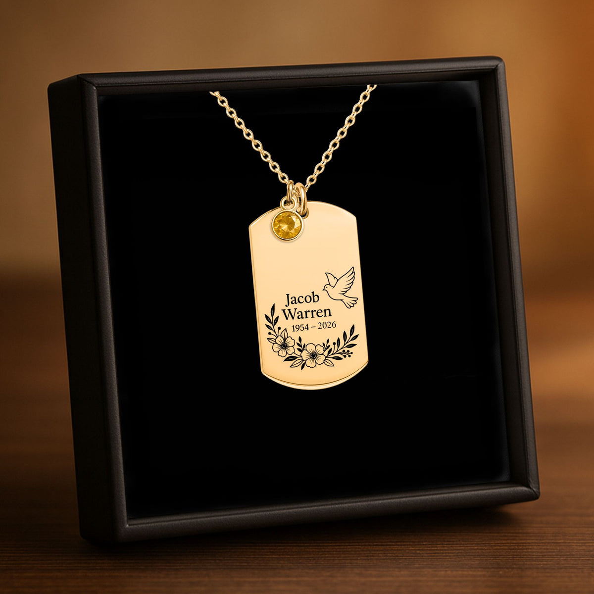 De ketting met gegraveerd plaatje met geboortesteen in goud, in een geschenkdoosje
