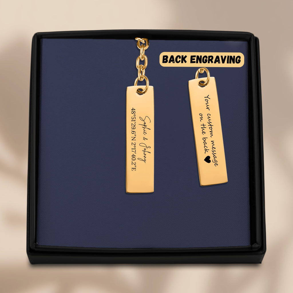De gouden staafsleutelhanger in het geschenkdoosje, met de achterkant ernaast