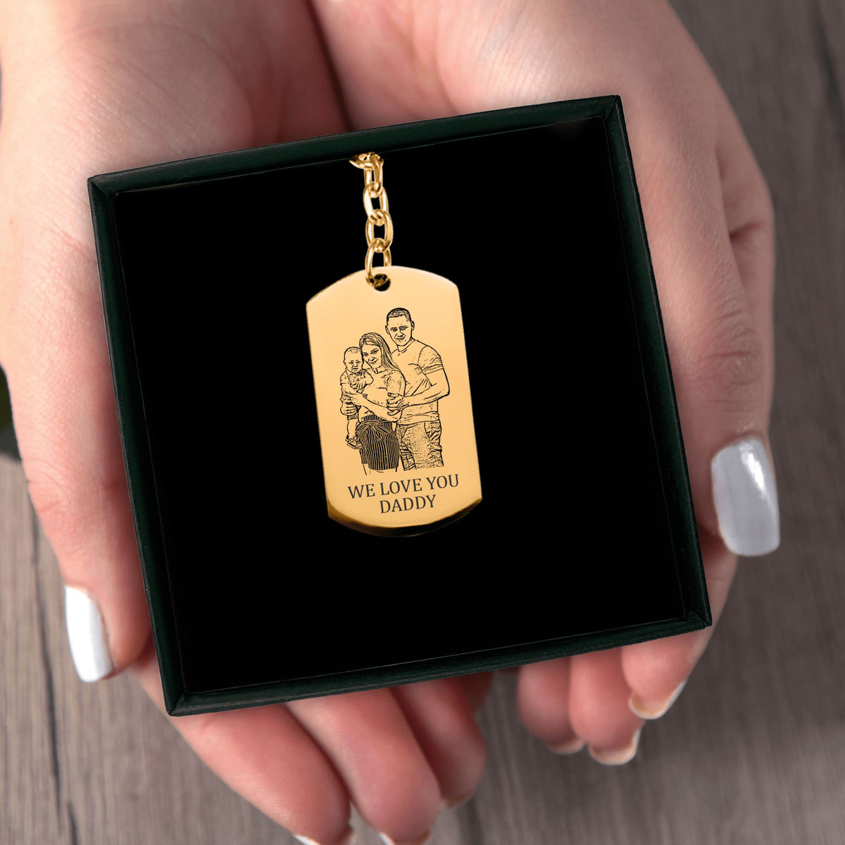 Het geschenkdoosje met de gouden sleutelhanger met gegraveerd plaatje, in twee handen