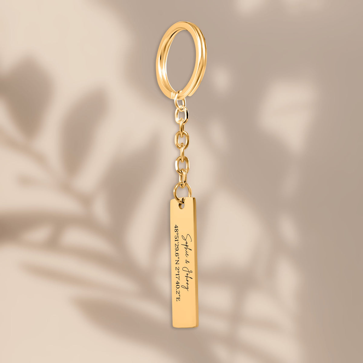 De gouden staafsleutelhanger, hangend tegen een beige achtergrond