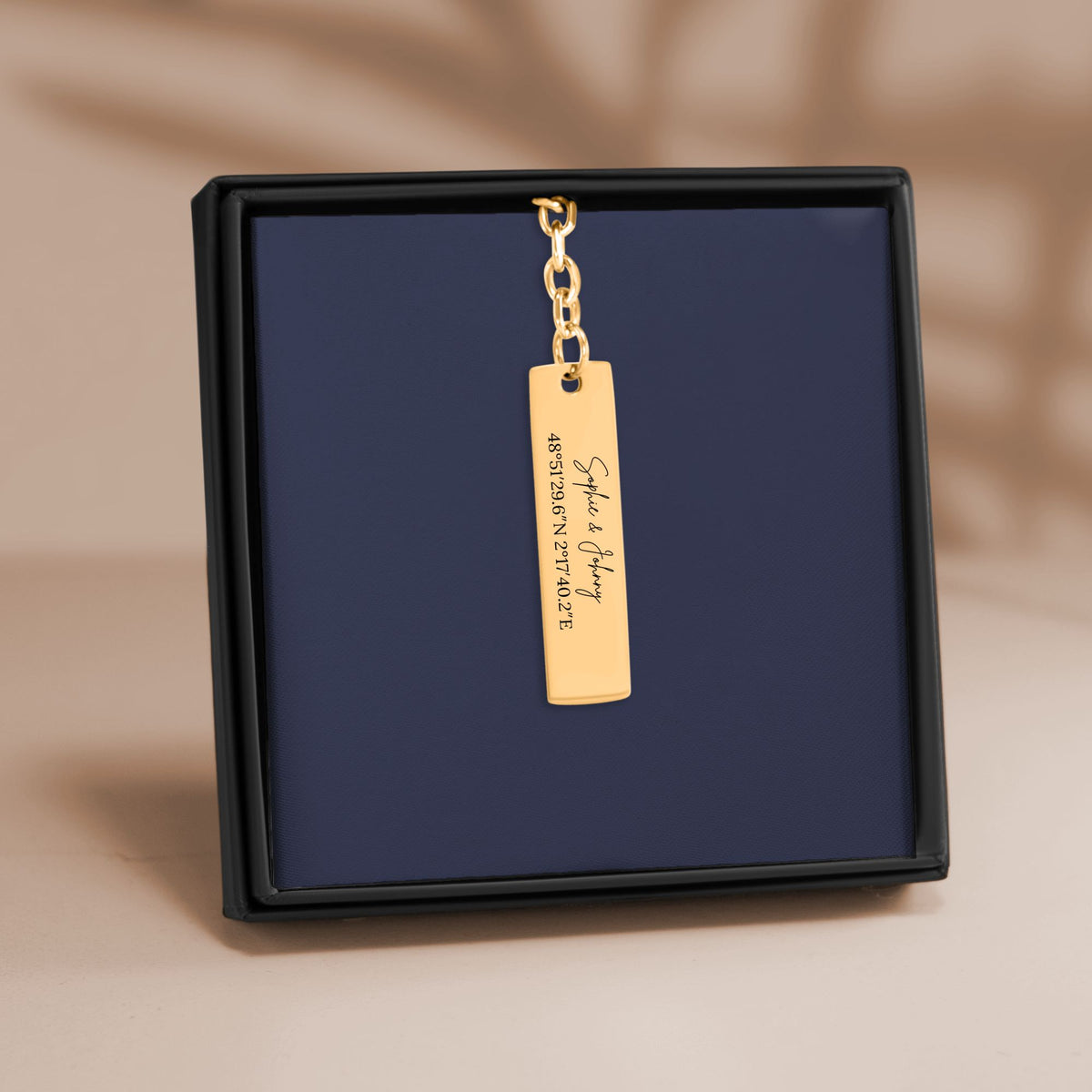 De staafsleutelhanger in goud, in een geschenkdoosje