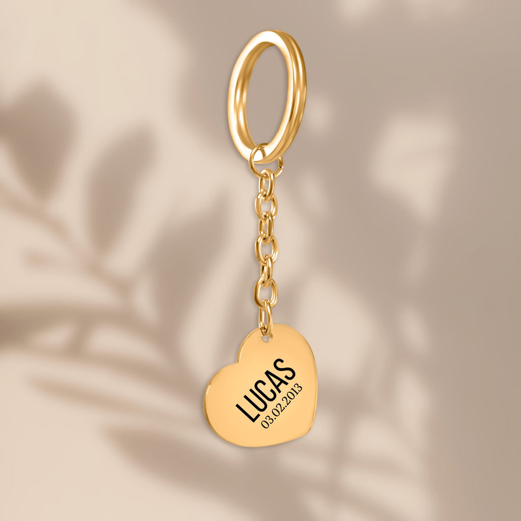 De gouden hartvormige sleutelhanger, hangend tegen een beige achtergrond
