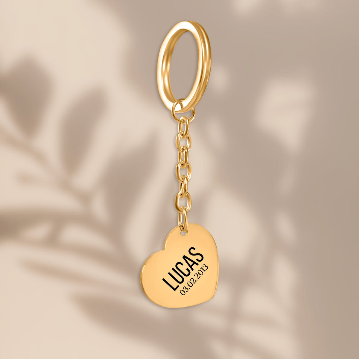 De gouden hartvormige sleutelhanger, hangend tegen een beige achtergrond