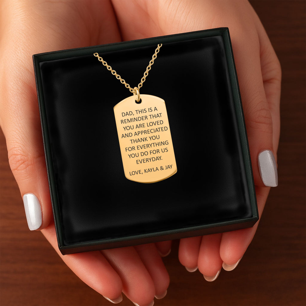 Het geschenkdoosje met de gouden ketting met gegraveerd plaatje, in twee handen