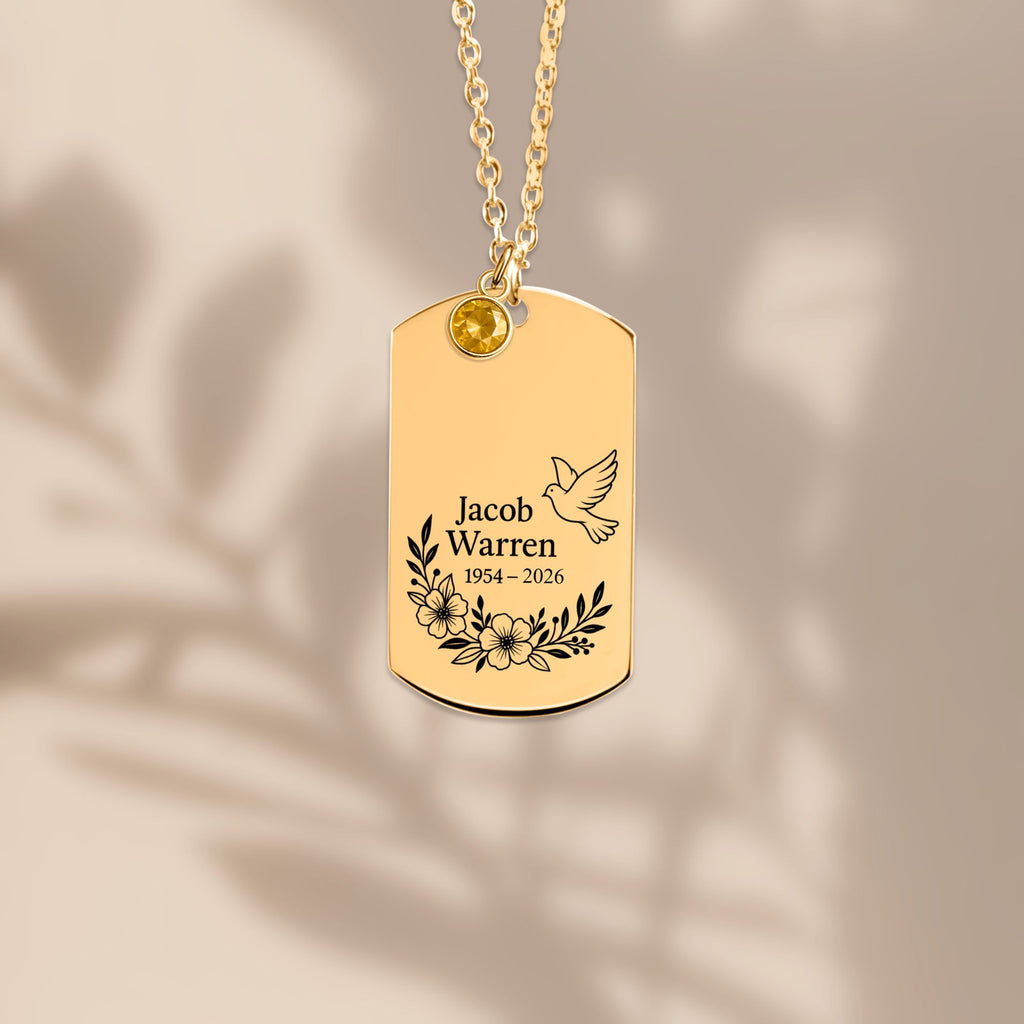De gouden ketting met gegraveerd plaatje, liggend tegen een lichte achtergrond