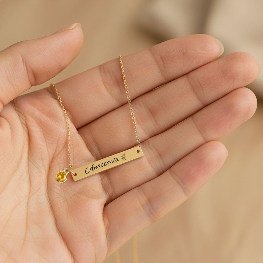 De gouden horizontale staafketting met geboortesteen in een handpalm