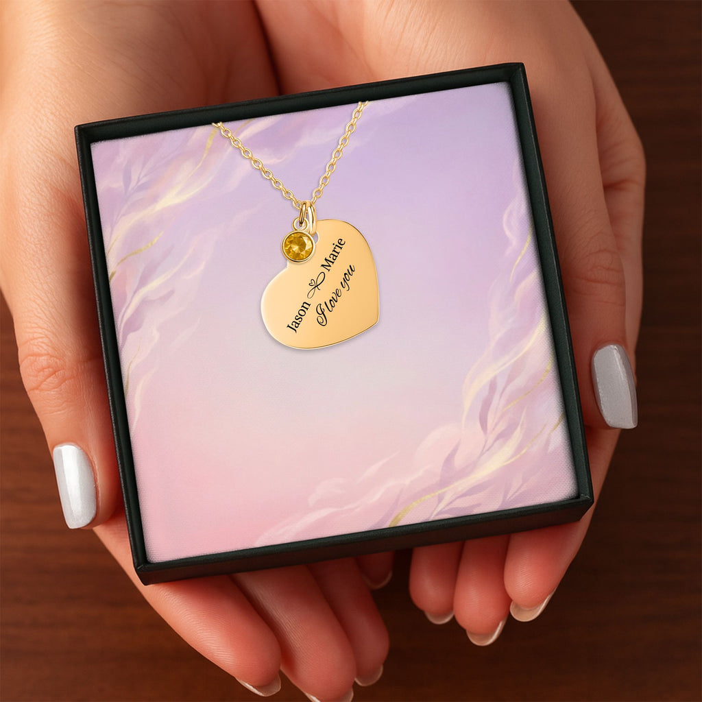 Het geschenkdoosje met de gouden hartketting met geboortesteen, in twee handen
