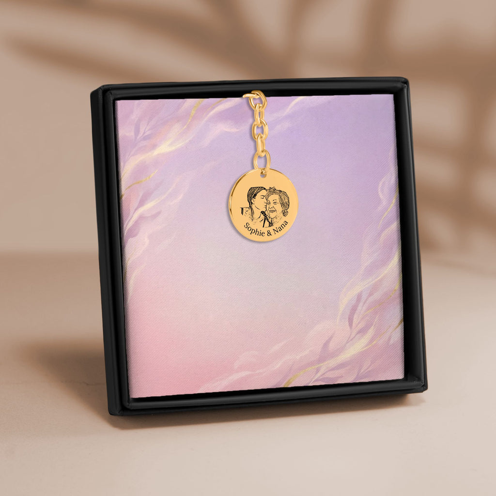 De muntsleutelhanger met lijnportret in goud, in een geschenkdoosje