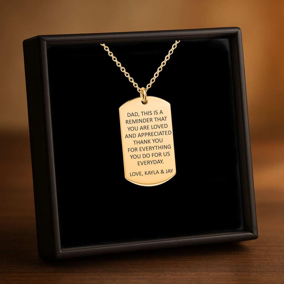 De ketting met gegraveerd plaatje in goud, in een geschenkdoosje