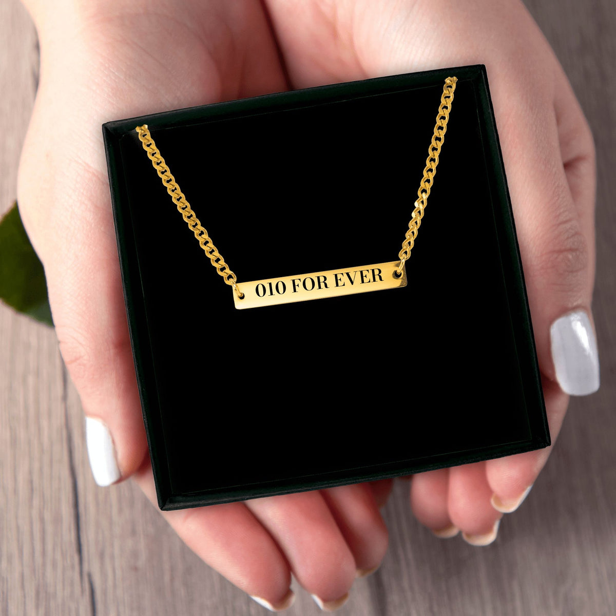Het geschenkdoosje met de gouden 010-ketting, in een hand