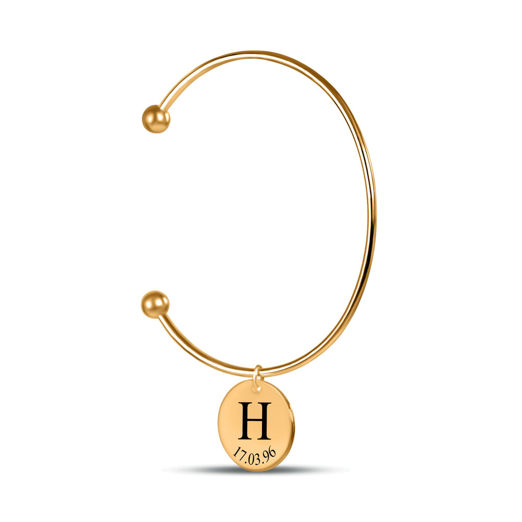 De gouden bangle met gegraveerde ronde hanger, tegen wit