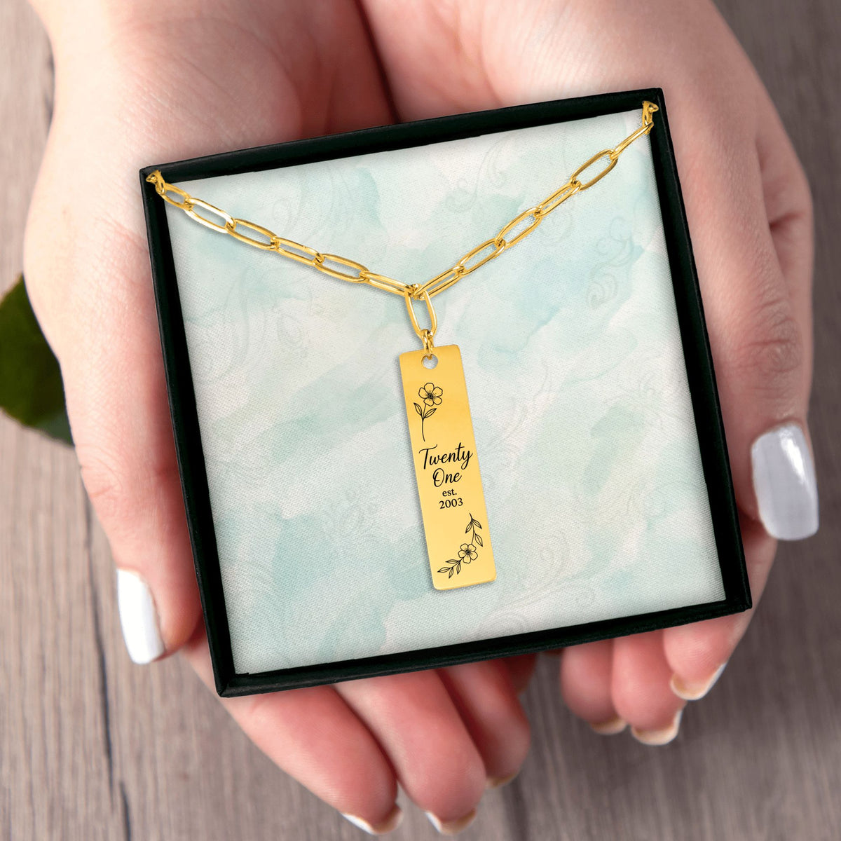 Het geschenkdoosje met de gouden paperclipketting, in een hand