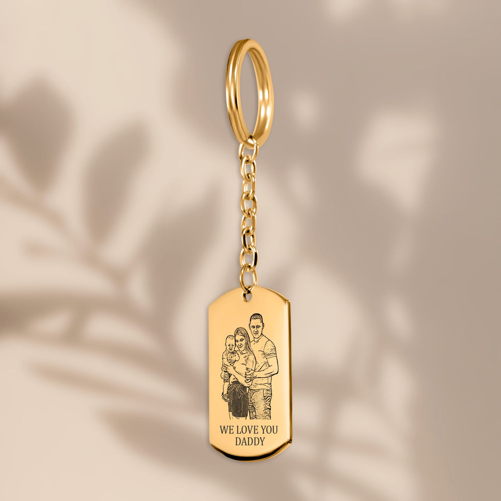 De gouden sleutelhanger met gegraveerd plaatje, hangend tegen een beige achtergrond