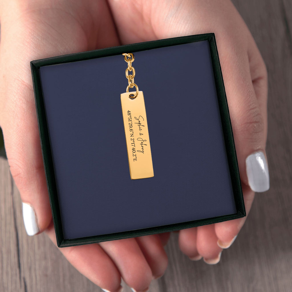 Het geschenkdoosje met de gouden staafsleutelhanger, in twee handen