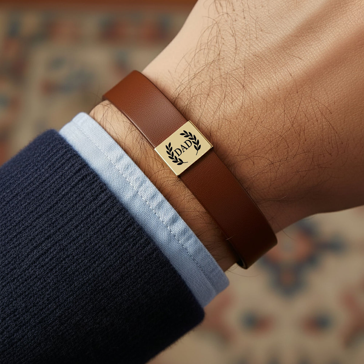 De bruine herenarmband van kunstleer met gegraveerd gouden plaatje, om een pols