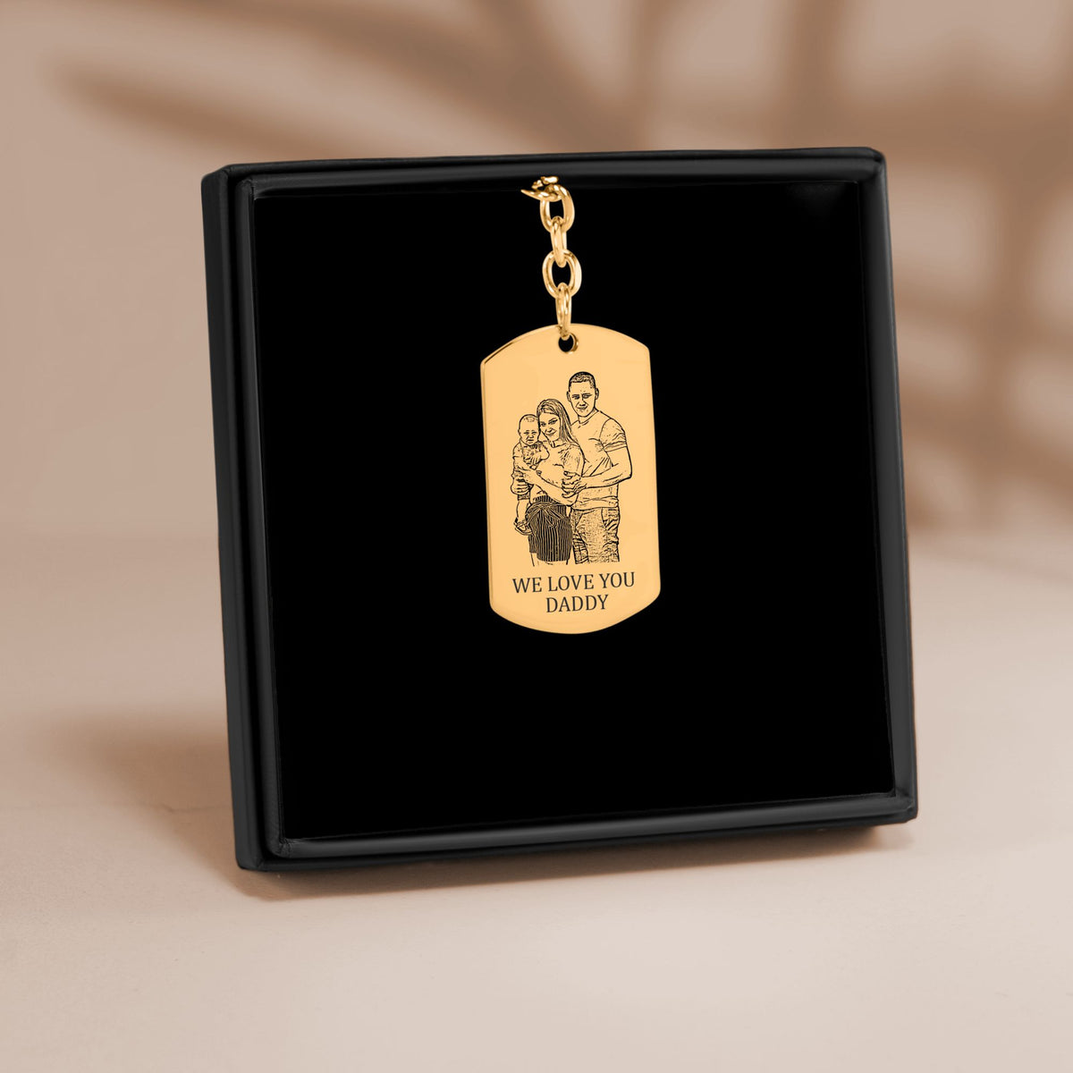 De sleutelhanger met gegraveerd plaatje in goud, in een geschenkdoosje