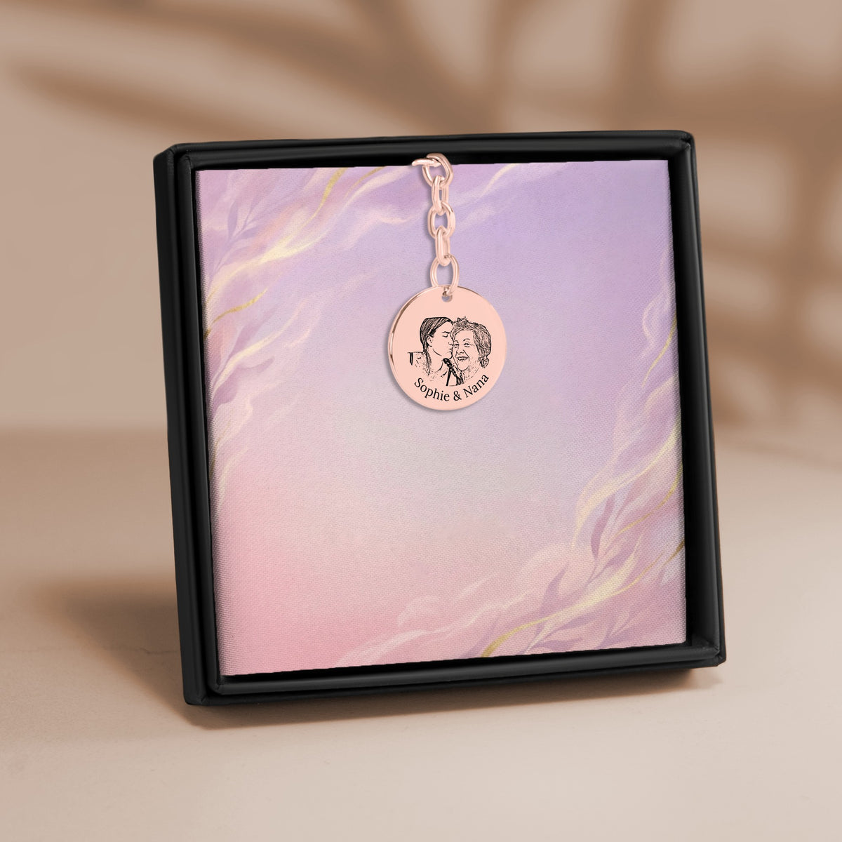 De muntsleutelhanger met lijnportret in roségoud, in een geschenkdoosje