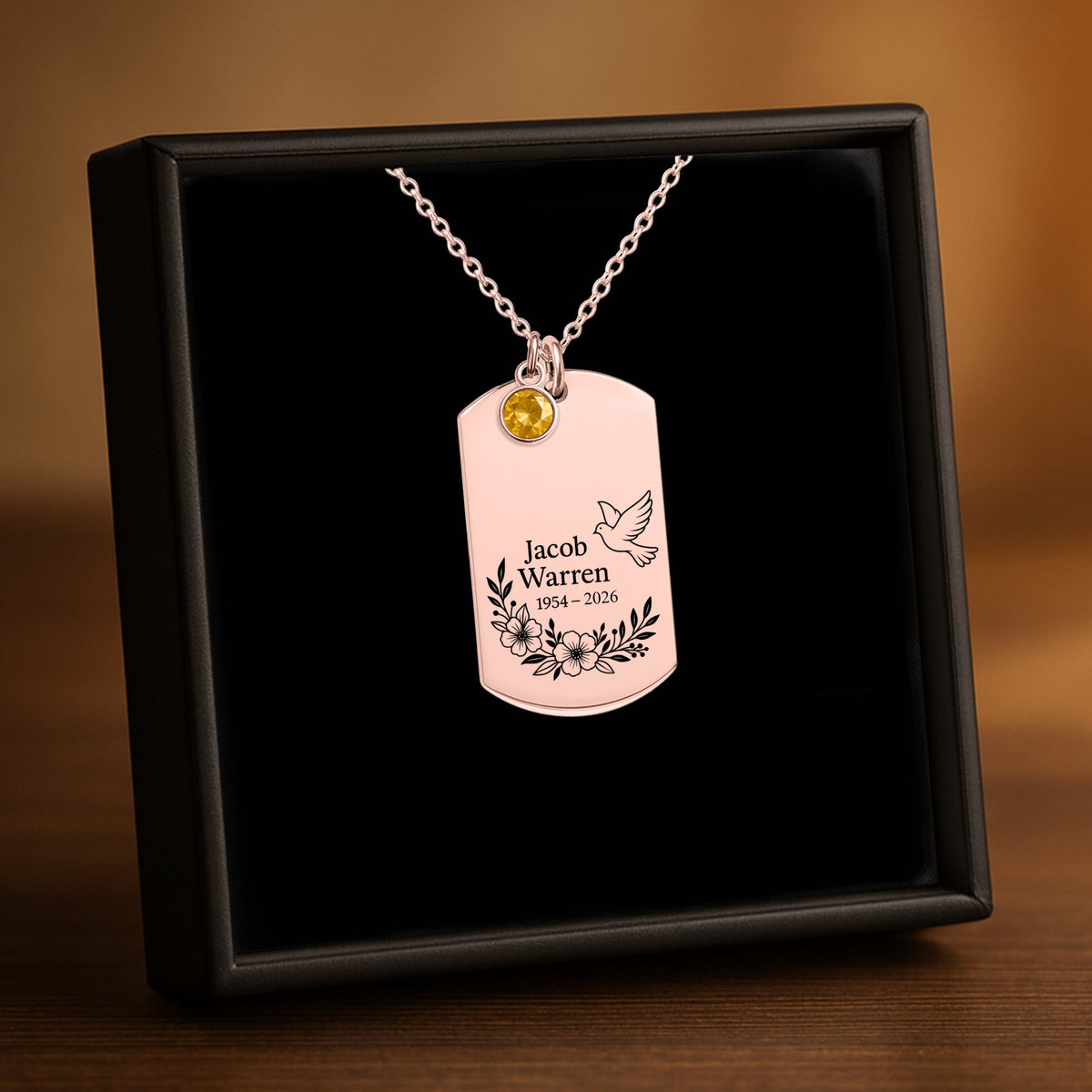 De ketting met gegraveerd plaatje met geboortesteen in roségoud, in een geschenkdoosje