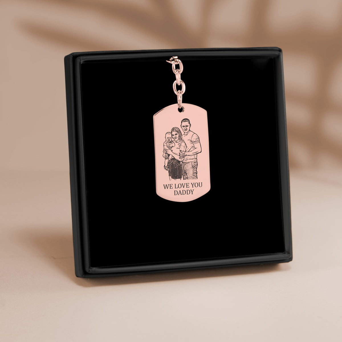 De sleutelhanger met gegraveerd plaatje in roségoud, in een geschenkdoosje