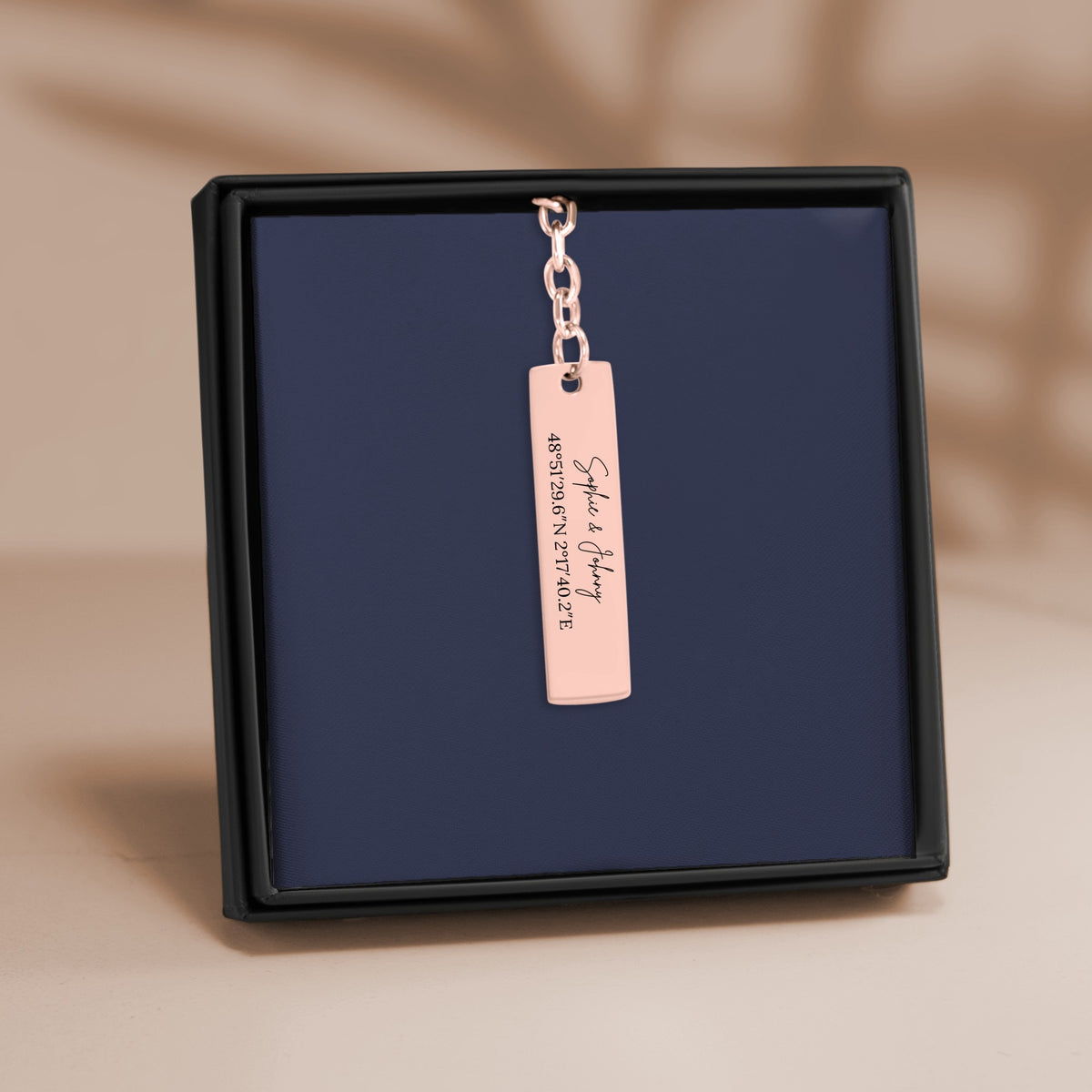 De staafsleutelhanger in roségoud, in een geschenkdoosje
